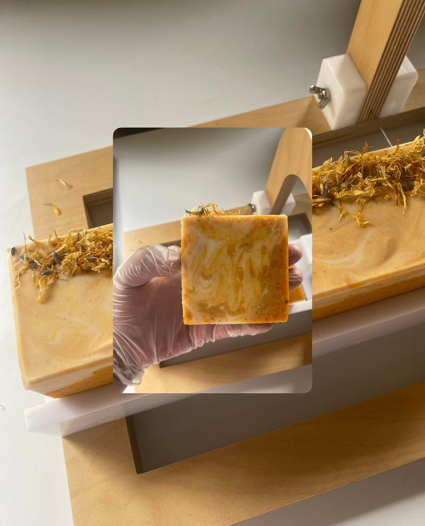 Handmade soap with natural elements on a wooden tray, held by a gloved hand.