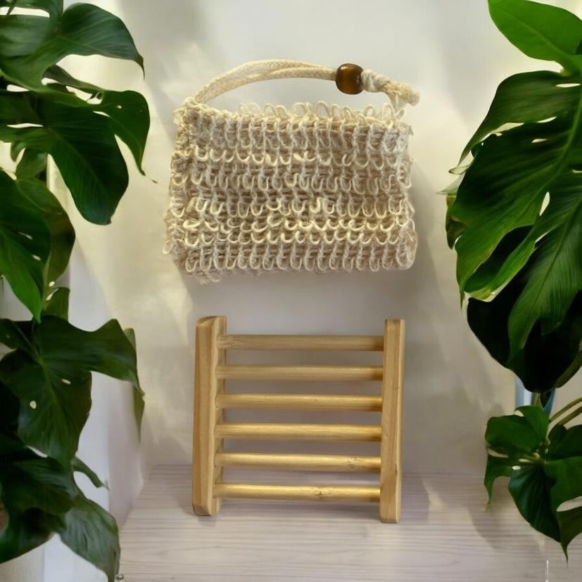 Sisal bag and wooden Soap holder against a light background with plants on either side